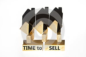 Time to sell house symbol. Concept words `Time to sell` on wooden blocks near miniature houses from shadows. Beautiful white