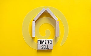 Time to sell house symbol. Concept words `Time to sell` on wooden blocks near miniature house. Beautiful yellow background, copy