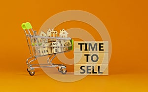 Time to sell real estate symbol. Wooden blocks, words `time to sell` on beautiful orange background. Shopping cart with miniatur