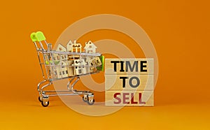 Time to sell real estate symbol. Wooden blocks, words `time to sell` on beautiful orange background. Shopping cart with miniatur