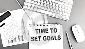 TIME TO SET GOALS text written on notebook on grey background with chart and keyboard , business concept
