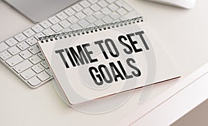 TIME TO SET GOALS text written on a notebook on grey background with chart and keyboard , business concept