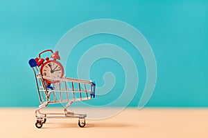 Time to shop. Purchasing of goods. Shopping concept. Time-limit, stopwatch. Trolley with red alarm clock, copy space