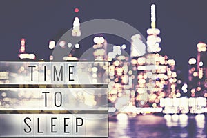 Time to sleep text in a lightbox, blurred Manhattan at night.