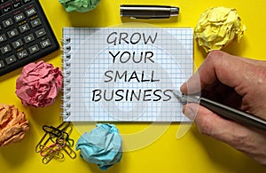 Time to small business. Mail hand writing `grow your small business` on white note, beautiful yellow background, colored paper