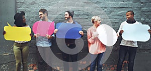 Time to speak up. a diverse group of people holding up speech bubbles against a gray brick wall.