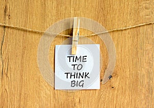 Time to think big symbol. Concept words Time to think big on beautiful white paper on clothespin. Beautiful wooden background.