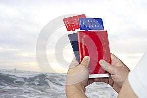 Time To Travel. The guy holds plane tickets and passports in his hands against the background of the sea