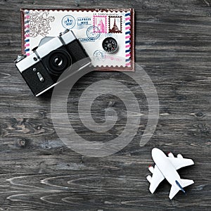 Time to travel, time to relax. Retro camera, white model of airplane, envelope for travel, compass on aged wooden background.