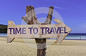 Time to Travel wooden sign with a beach on background photo