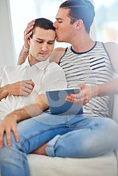 Time together is always a good time. Shot of an affectionate gay couple using a digital tablet while relaxing on the