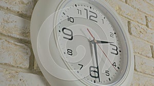 Time two hours thirty minutes. Timelapse. Round white clock hanging on brick wall.