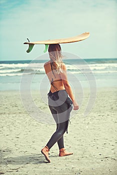 Time for a water adventure. a beautiful young woman going for a surf at the beach.