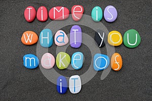 Time is what you make of it, wise words composed with multicolored stone letters over black sand
