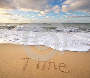 Time word on the sea sand.