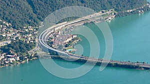 Timelapse, aerial view on cars and trains traffic in Swiss Alpine town near lake. Melide causeway, Bissone, Lake Lugano, Canton
