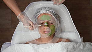 Timelapse beautician applying a green mask to face