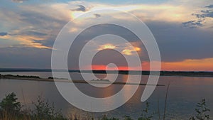 Timelapse of a beautiful sunset over a river with sky and clouds, light reflections in the water. landscape