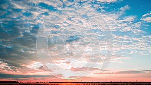 Timelapse, a bright sunset with leaking clouds and a passing passenger train.