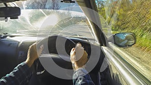 A timelapse of a car driving along a narrow country road. View from the car of the steering wheel and the driver's hands