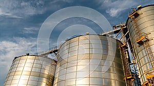 Timelapse of cloud movement. silver silos on agro manufacturing plant for processing drying cleaning