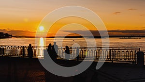 Timelapse - couple admiring dramatic colorful golden susnet on river at quay