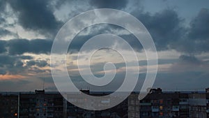 Timelapse of dramatic skyline over urban landscape. Clouds move swiftly above city buildings as dusk transitions to