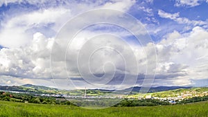 Timelapse follow of a rain rainbow cloud shining through the landscape with moving thick clouds in the sky and shadows and stops