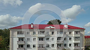 Timelapse the movement of clouds over a multi-storey residential building with a new red roof. The concept of renting a home