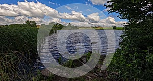 Timelapse, moving clouds over small pond in summertime