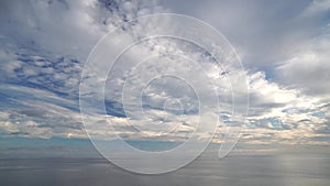 Timelapse multilayered Cirrus and Cumulus clouds moving in bright sunset sky over calm sea. Abstract aerial nature