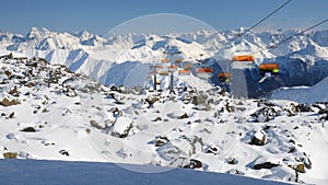 Timelapse of orange chairlft above rocky terrain, in Samnaun - Ischgl - Paznaun ski resort, located in Austria and Switzerland.