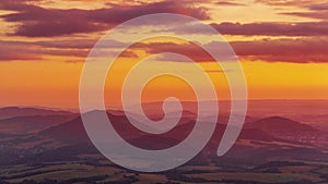 Timelapse of an orange-golden sunset over the Beskydy Mountains and the surrounding landscape with villages lying in a valley Gold