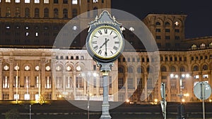 Timelapse of public clock at Palace of Parliament, Bucharest, Romania, partly illuminated at night to reduce energy costs.