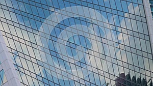 Timelapse - reflection of moving white clouds in glass wall of skyscraper