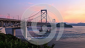 Timelapse of strong current flowing under suspension bridge at sunset