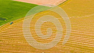 Timelapse Time lapse Dronelapse Hyperlapse. Aerial View Top View Of Tractor Collects Dry Grass In Straw Bales In Wheat