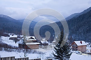 Timelapse of wooden cottages in mountain village valley surrounded with coniferous forest and snowy mountains. Fast view