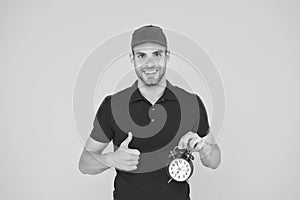 Timeliness guarantee. Promptness and punctuality. Delivery time. Delivery courier with clock. Delivery man holding clock photo