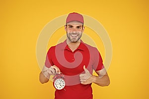 Timeliness guarantee. Promptness and punctuality. Delivery time. Delivery courier with clock. Delivery man holding clock photo