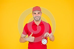 Timeliness guarantee. Promptness and punctuality. Delivery time. Delivery courier with clock. Delivery man holding clock