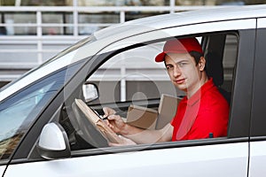Timely home delivery by car. Courier in auto makes entry in tablet