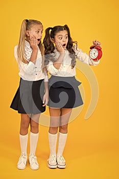 Timing is time study. Stressed little children looking at clock with timing signal on yellow background. Small girls in