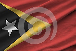 Timor Leste flag with big folds waving close up under the studio light indoors. The official symbols and colors in photo