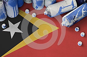 Timor Leste flag and few used aerosol spray cans for graffiti painting. Street art culture concept photo