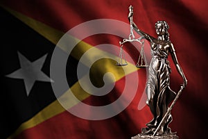 Timor Leste flag with statue of lady justice and judicial scales in dark room. Concept of judgement and punishment photo