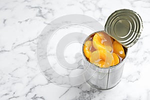 Tin can with conserved peach halves on marble background