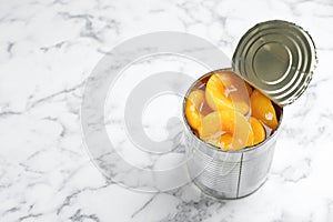 Tin can with conserved peach halves on marble background photo