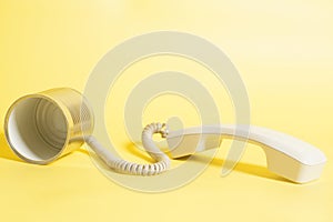 Tin can phone with handset on yellow background