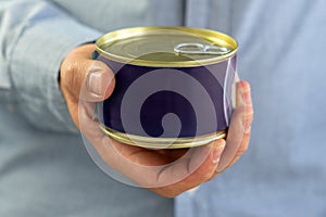 Tin can with ring in male hand. Close up. an empty label for design and text. Copy Space